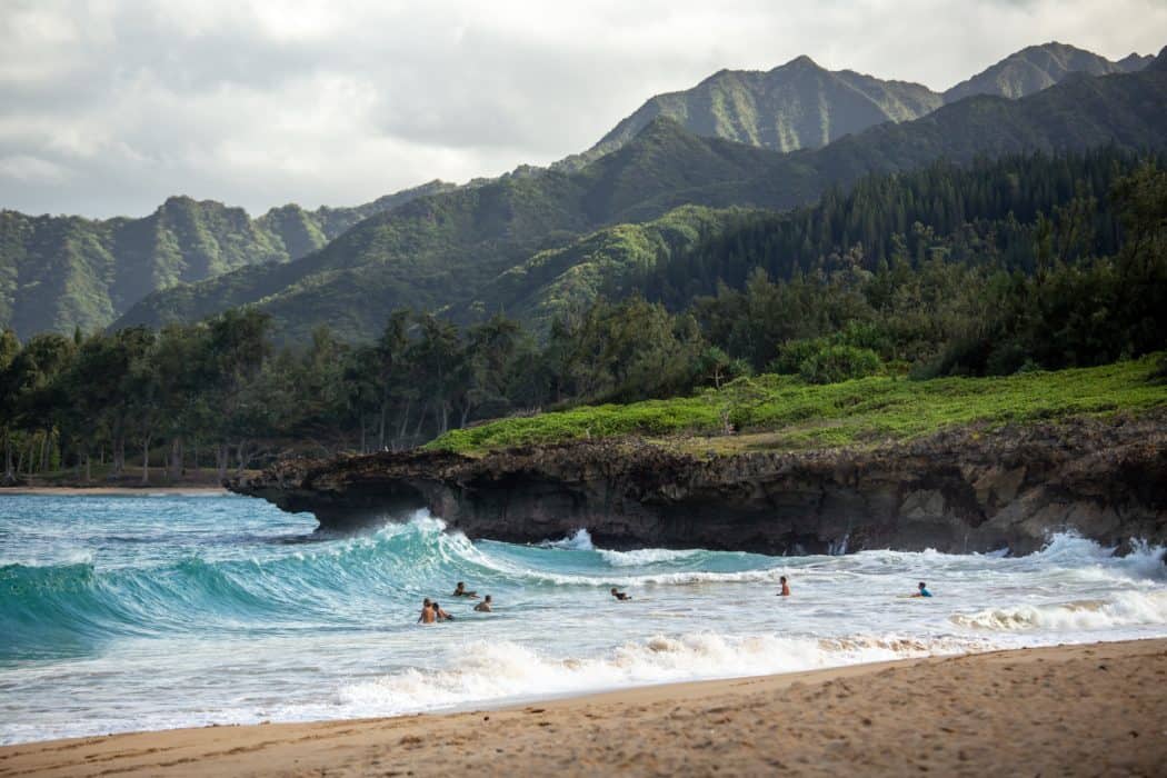 a beach in hawaii with people playing in the ocean