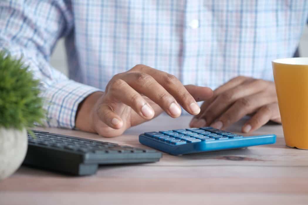 Person sitting at a table with a calculator going over their finances