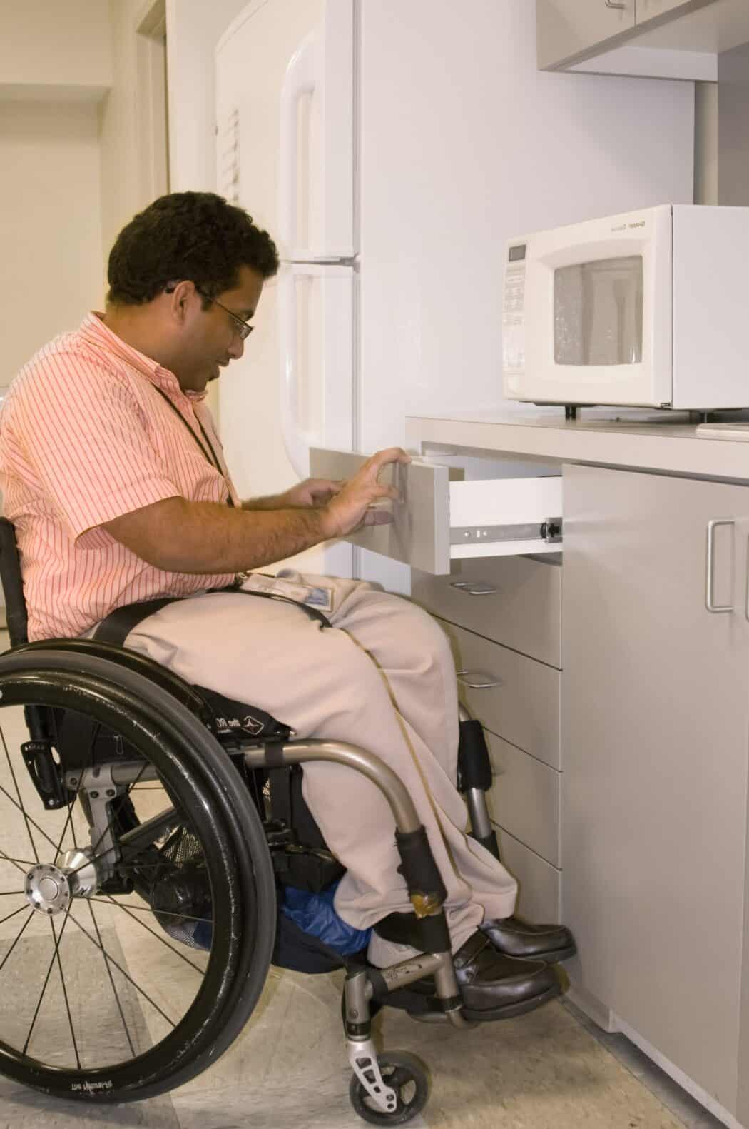 Man in a wheelchair opening a kitchen drawer