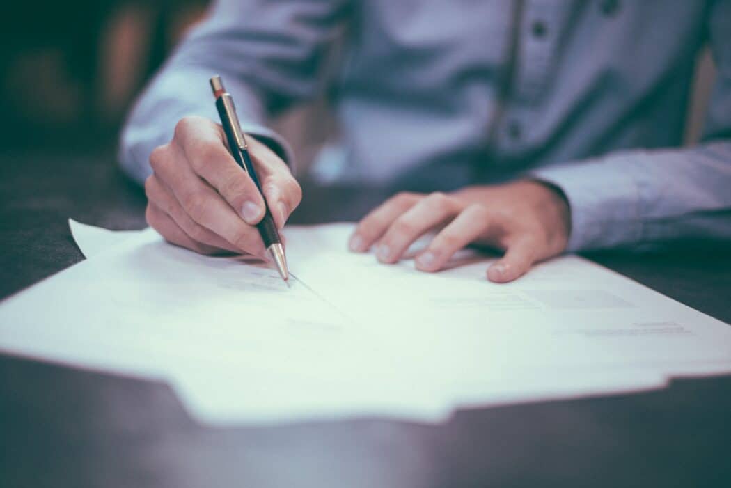 Person signing papers on a table with a pen