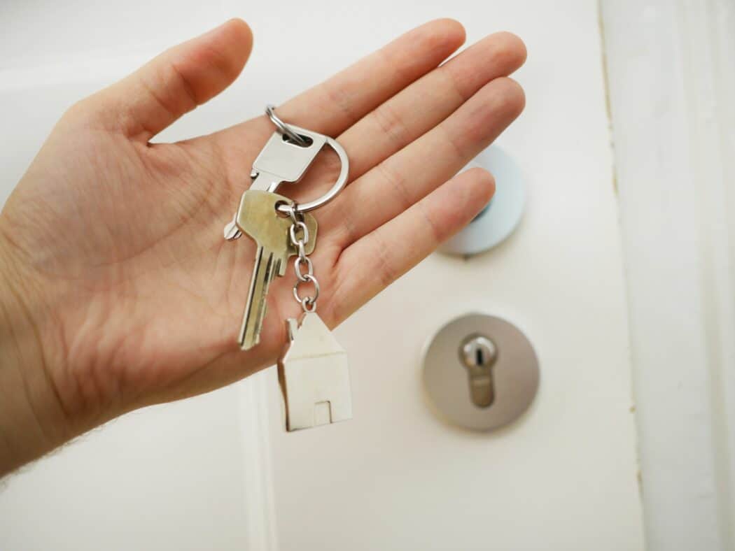 A person holding keys by a door